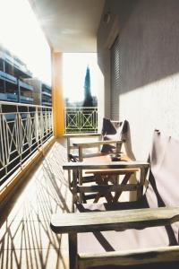 a balcony with wooden tables and chairs on a building at Gk Suites-Constantin view , auto check-in 24h in Larisa