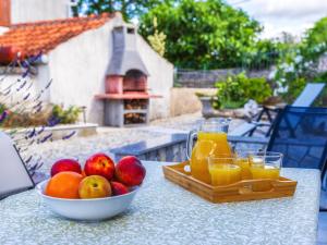 a bowl of fruit and glasses of orange juice on a table at House Villa Katarina in Malinska