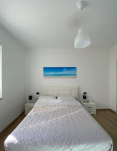 Un dormitorio blanco con una cama y un cuadro en la pared. en Appartamenti Palinuro Isca, en Palinuro