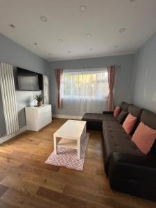 a living room with a black couch and a table at Dana’s bungalow in Horley