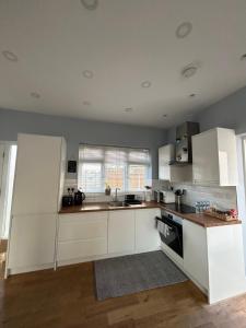 a kitchen with white cabinets and a counter top at Dana’s bungalow in Horley