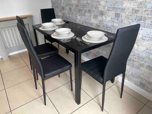 a black dining table with chairs and plates on it at Tranquil Haven: 3-BR House in Great Burstead