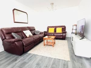 a living room with a brown leather couch and a table at Tranquil Haven: 3-BR House in Great Burstead