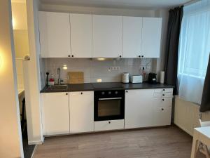 a kitchen with white cabinets and a black counter top at Stylish Apartment in Friesenplatz, Heart of Cologne in Cologne