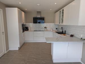 a white kitchen with white cabinets and a sink at Flotun in Stryn