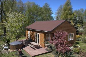 a small cabin with a deck and a hot tub at Kempings "Ceļmalnieki" in Liepāja