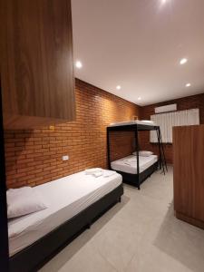 2 camas en una habitación con una pared de ladrillo en Bee Cool Hostel, en Palmas