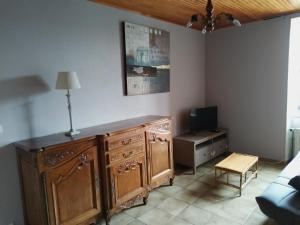 a living room with a wooden dresser and a tv at Sainte Eulalie source de la loire in Sainte-Eulalie