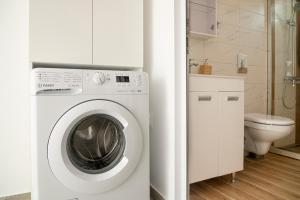 een witte wasmachine in een badkamer met een toilet bij Gabi's Seabreeze Nest in Nea Kalikratia