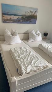 2 camas con sábanas y almohadas blancas en Arkonablick 53, en Juliusruh