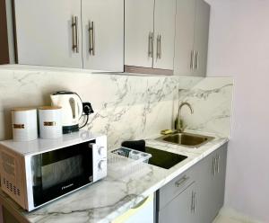 a kitchen counter with a microwave and a sink at Anemos Studios & Apartments in Póros Kefalonias