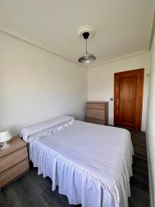 a bedroom with a white bed and a wooden cabinet at Miguelón in Bañugues