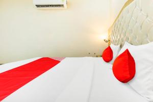 Super OYO Collection O Hotel White Prime في فاغوارا: غرفة نوم مع وسائد حمراء وبيضاء على سرير