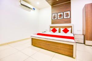 Super OYO Collection O Hotel White Prime في فاغوارا: غرفة نوم بسرير كبير ومخدات حمراء