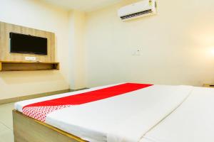 Super OYO Collection O Hotel White Prime في فاغوارا: غرفة نوم مع سرير وتلفزيون على الحائط