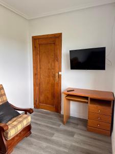 a room with a desk and a television on a wall at Miguelón in Bañugues