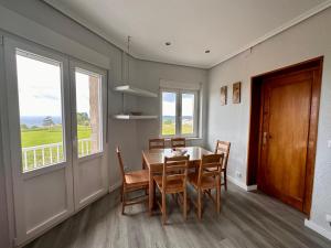 a dining room with a table and chairs and windows at Miguelón in Bañugues
