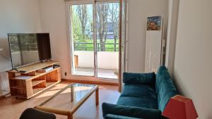 Una sala de estar con un sofá verde y un televisor. en Appartement de 60m2 dans une belle résidence calme, en Neuilly-sur-Marne