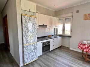 a kitchen with white cabinets and a refrigerator at Miguelón in Bañugues +10 photos