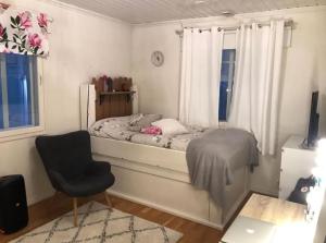 Un dormitorio con una cama y una silla y una ventana. en Uudehko tunnelmallinen talo, en Venesjärvi