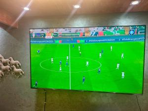 - une télévision suspendue sur un mur avec un match de football dans l'établissement Vila Alexander B&B, à Valbonë