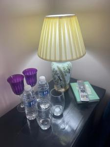 a table with a lamp and some glasses and water bottles at Boutique Shrewsbury Rooms in Shrewsbury