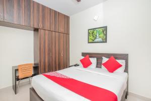 1 dormitorio con cama con almohadas rojas y escritorio en Manyata Royal Mac, en Bangalore