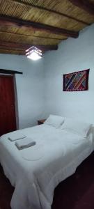 - une chambre avec un grand lit blanc et une fenêtre dans l'établissement Hostal Mamacoca, à Purmamarca