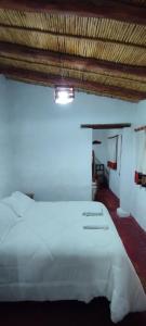um quarto com uma grande cama branca num quarto em Hostal Mamacoca em Purmamarca