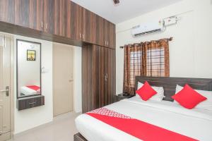 a bedroom with a large bed with red pillows at Manyata Royal Mac in Bangalore