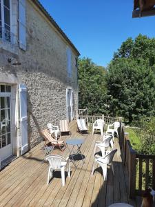 a deck with chairs and tables and a building at Maison entre Terre et Mer in Curzon