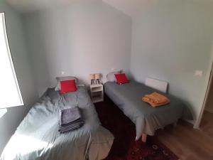 two beds in a small room with red pillows at Maison entre Terre et Mer in Curzon