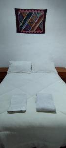 uma cama branca com duas toalhas em cima em Hostal Mamacoca em Purmamarca