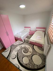 two beds in a room with a carpet at The Hill House in Prizren