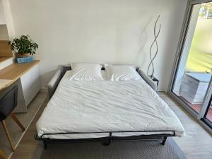 een bed met witte lakens en kussens in een kamer bij Le Capitole - Studio Plage Benoit - Escapade Hivernale in La Baule