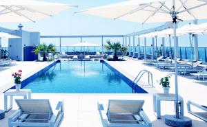 una piscina con sillas y sombrillas en un edificio en Marjan Island Beautiful Apartment Sea Side View Beach Luxury Rooms Ras Al Khaimah UAE, en Ras al Khaimah