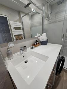 een badkamer met een witte wastafel en een spiegel bij Le Capitole - Studio Plage Benoit - Escapade Hivernale in La Baule