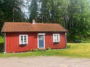 czerwony dom z dwoma oknami i niebieskimi drzwiami w obiekcie Sjönära stuga Bottnaryd w mieście Bottnaryd