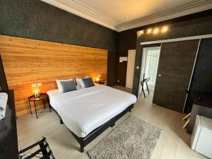 a bedroom with a large white bed with a wooden headboard at La Villa Blanche Spa in Spa