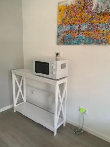 a white table with a tv and a painting on the wall at OnlyRoomsRho in Rho