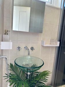 uma casa de banho com um lavatório de vidro e um espelho. em Dana guest suite em Horley