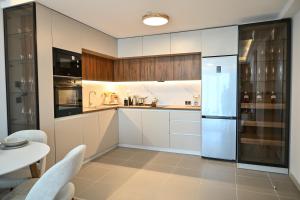 a kitchen with white cabinets and a white refrigerator at Portokali Sky Apartment in Skopje