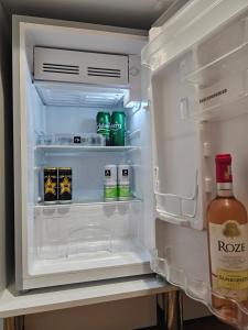 Un refrigerador abierto lleno de bebidas y una botella de salsa. en Central Bucharest Retreat, en Bucarest