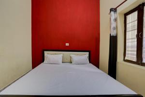 a bed in a room with a red wall at HOTEL SS PARADISE in Lucknow