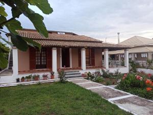 a house with a porch and flowers in the yard at Christodoulos Villa in Agios Georgios