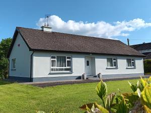 a white house with a black roof at Home from home in East Galway in Ballycrossaun