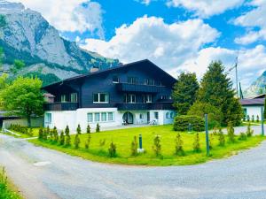 a house on a green lawn with mountains in the background at Modern designed, luxury mountain view Apartment in Kandersteg