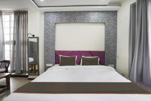 Schlafzimmer mit einem großen Bett mit einem lila Kopfteil in der Unterkunft Hotel City Pride in Raipur