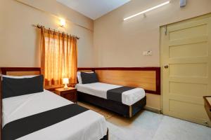 a hotel room with two beds and a door at SPOT ON Benaka Delux Lodging & Delux Rooms in Bangalore