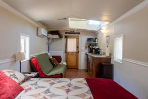 a bedroom with a bed and a chair and a kitchen at Little Red Caboose in Oakhurst